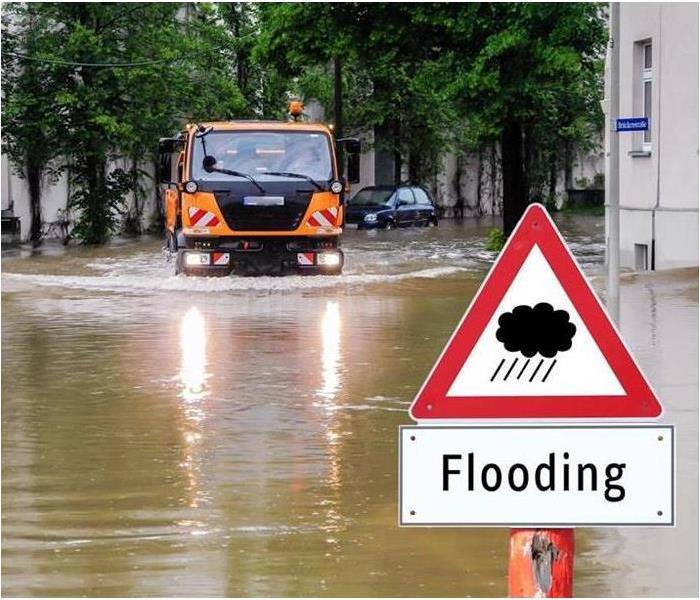 Heavy flooding with flooding sign and truck driving through water