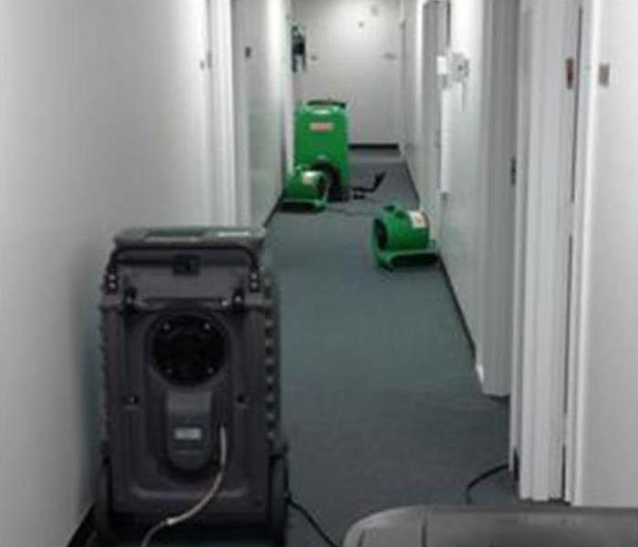 Two air movers and two dehumidifiers placed in a long hallway of a building